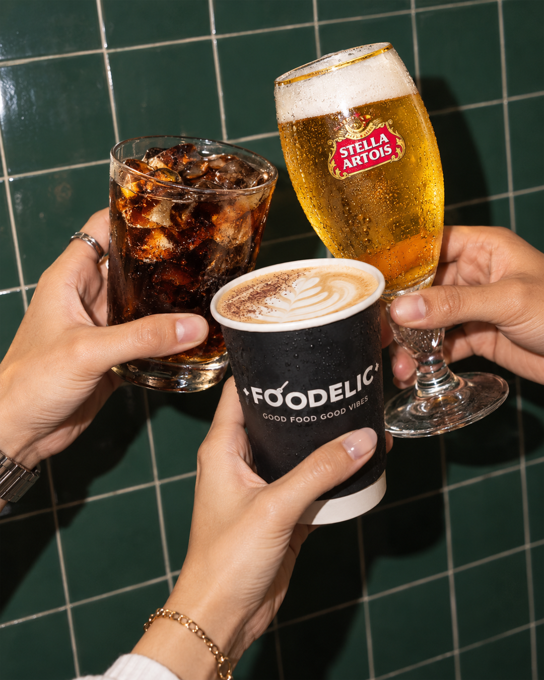 Friends clinking a cola, a Stella Artois beer, and a Foodelic latte together